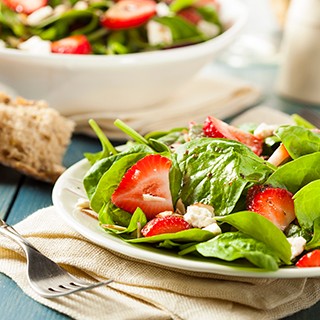 Mixed greens with strawberries with balsamic dressing on a plate