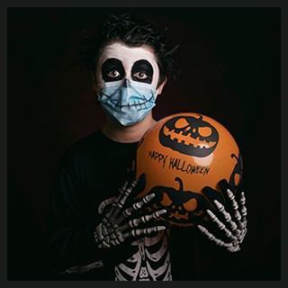 boy wearing scary makeup, skeleton costumer, wearing protective mask, holding decorated orange balloon