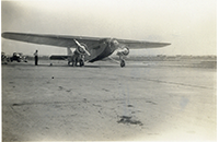 Ford Trimotor Aircraft on Tarmac with Trucks Parked Behind, photograph, circa 1920s or 1930s