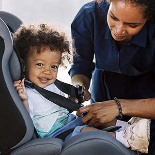 mother fixing child into safety seat